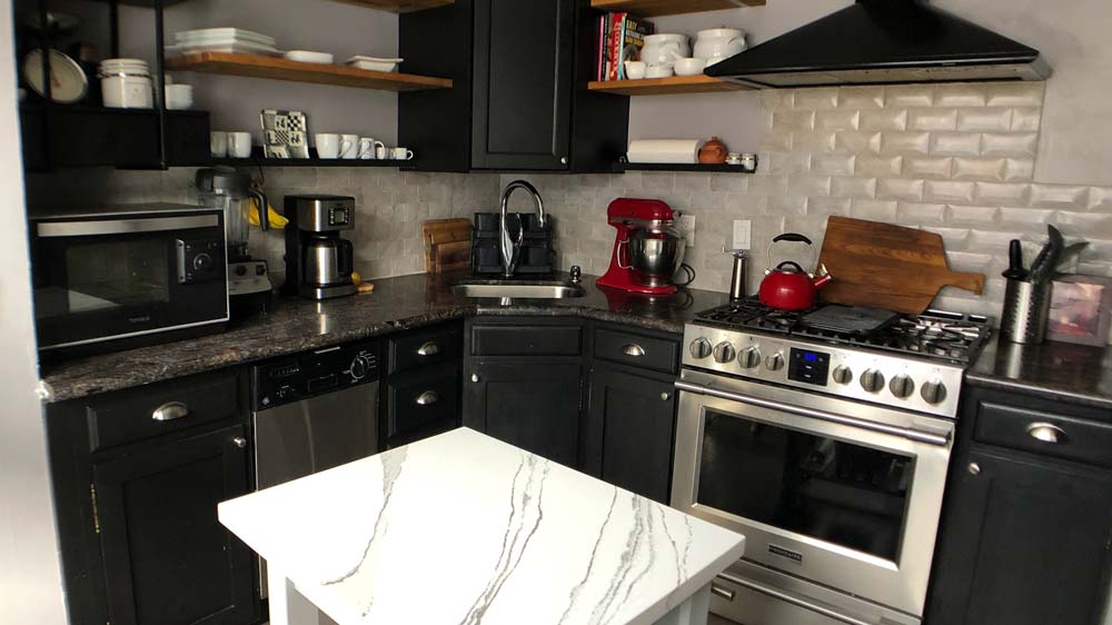 A kitchen with a stainless stell oven & vent hood