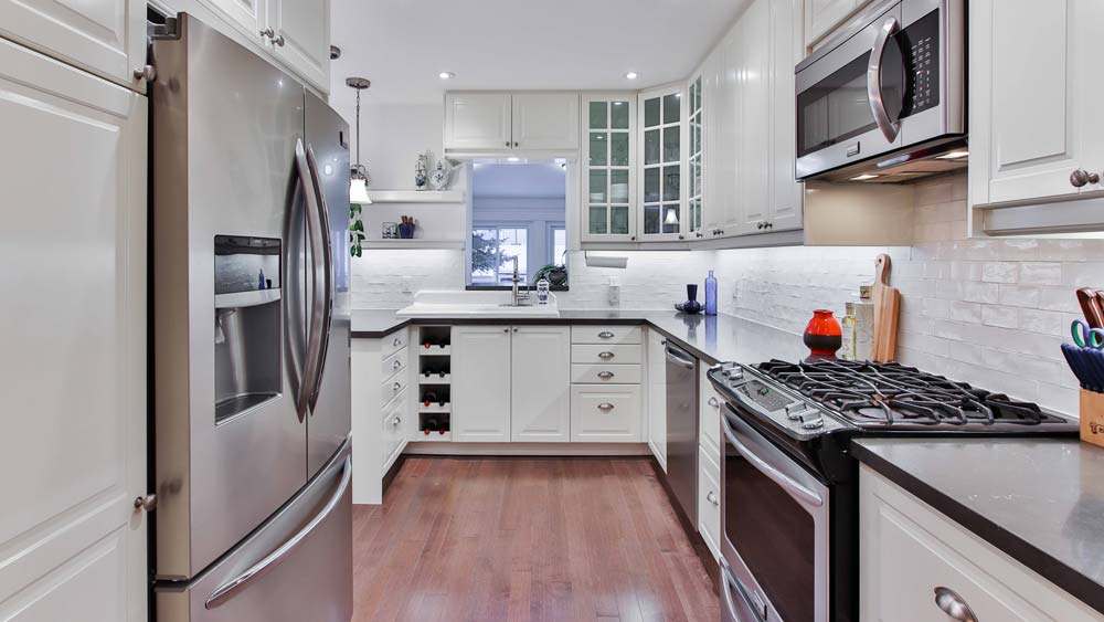 A kitchen with stainless steel appliances: a fridge, an oven, a microwave and a dishwasher.